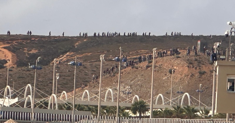 Una muchedumbre se acerca a la frontera por la colina próxima al Tarajal